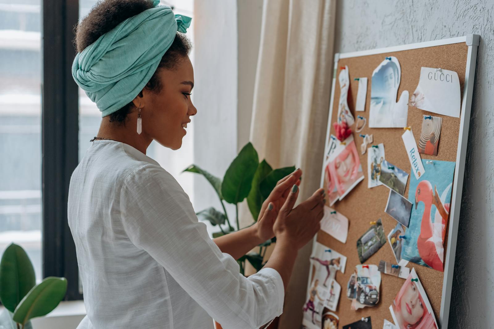 A woman arranging a creative mood board with diverse images and notes in a stylish interior.